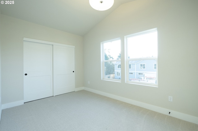 unfurnished bedroom with vaulted ceiling, a closet, and carpet flooring