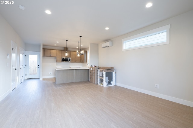 kitchen featuring a wall mounted AC, a notable chandelier, light hardwood / wood-style floors, decorative light fixtures, and kitchen peninsula