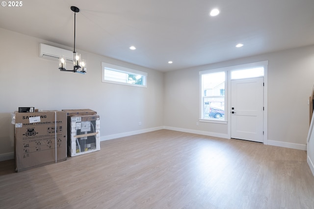 entrance foyer featuring an inviting chandelier, light hardwood / wood-style flooring, and a wall mounted AC