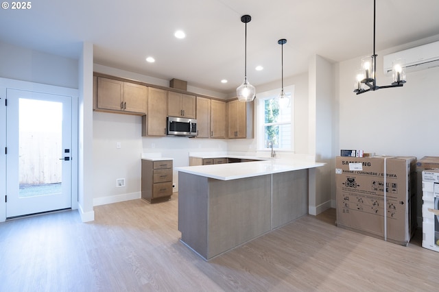 kitchen with hanging light fixtures, sink, light hardwood / wood-style flooring, and kitchen peninsula