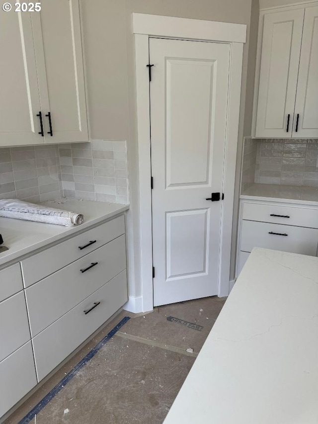 kitchen featuring decorative backsplash, white cabinets, and light stone countertops