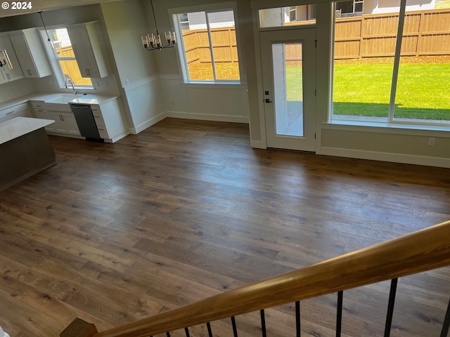 unfurnished dining area with sink, dark wood-type flooring, and a notable chandelier