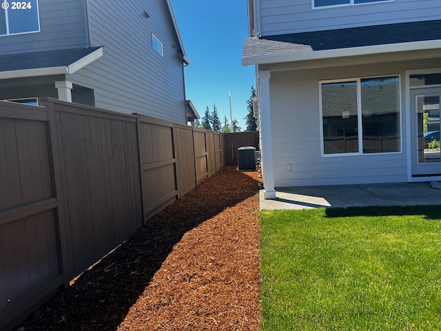 view of side of property with a yard, a patio, and central AC unit