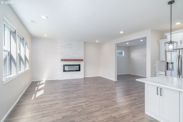 unfurnished living room with a stone fireplace and dark hardwood / wood-style flooring