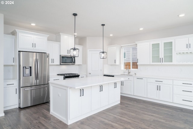 kitchen with stainless steel appliances, dark hardwood / wood-style flooring, a center island, white cabinetry, and decorative light fixtures