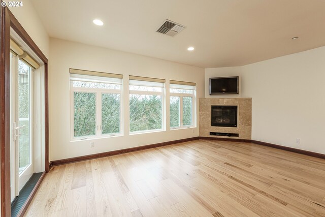 unfurnished living room with light hardwood / wood-style floors and a tile fireplace