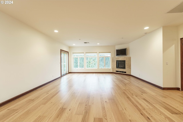 unfurnished living room with a tile fireplace and light hardwood / wood-style flooring