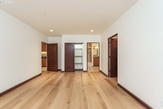 unfurnished bedroom featuring ensuite bathroom and light hardwood / wood-style flooring