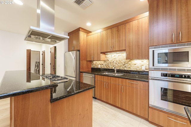 kitchen featuring island range hood, a kitchen island, dark stone counters, appliances with stainless steel finishes, and sink