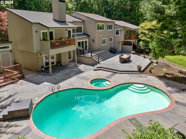 view of swimming pool featuring a wooden deck, an in ground hot tub, and a patio