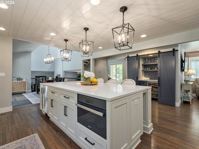 kitchen with dark hardwood / wood-style flooring, oven, a center island, a barn door, and decorative light fixtures