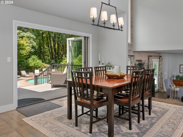 dining space with wood-type flooring, plenty of natural light, and an inviting chandelier