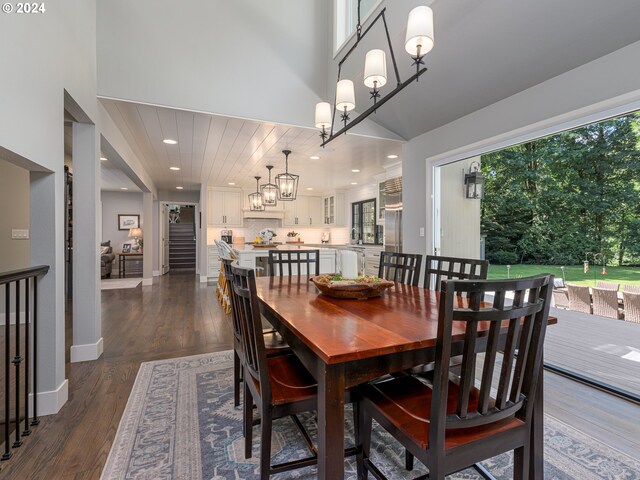 dining space with dark hardwood / wood-style flooring, a chandelier, and a towering ceiling