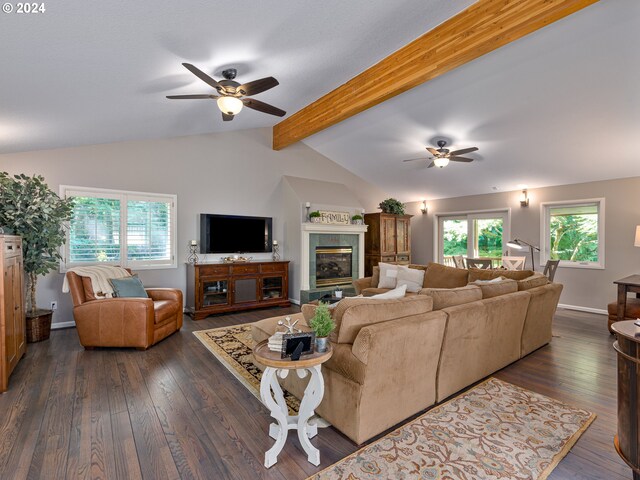 living room featuring a tiled fireplace, dark wood-type flooring, ceiling fan, and a healthy amount of sunlight