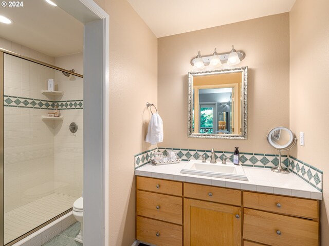 bathroom with toilet, vanity, and a shower with shower door