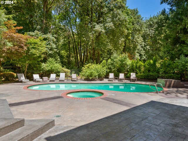 view of swimming pool featuring a patio and an in ground hot tub