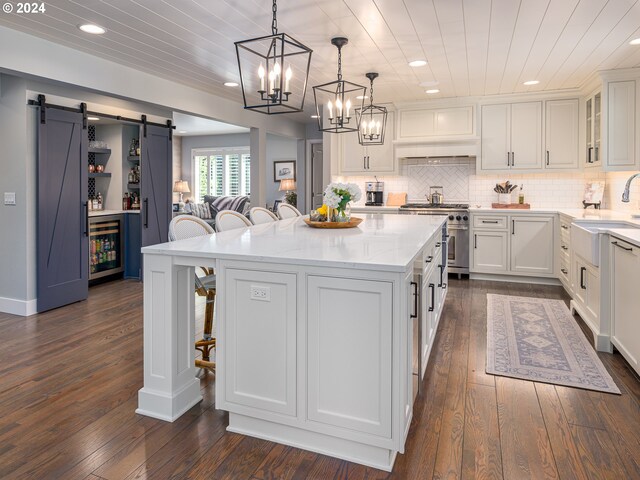 kitchen featuring a barn door, dark hardwood / wood-style floors, wine cooler, a breakfast bar, and a center island