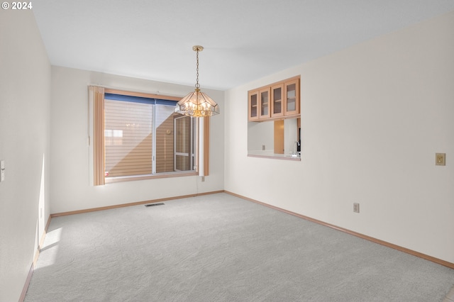 unfurnished room featuring an inviting chandelier and light colored carpet