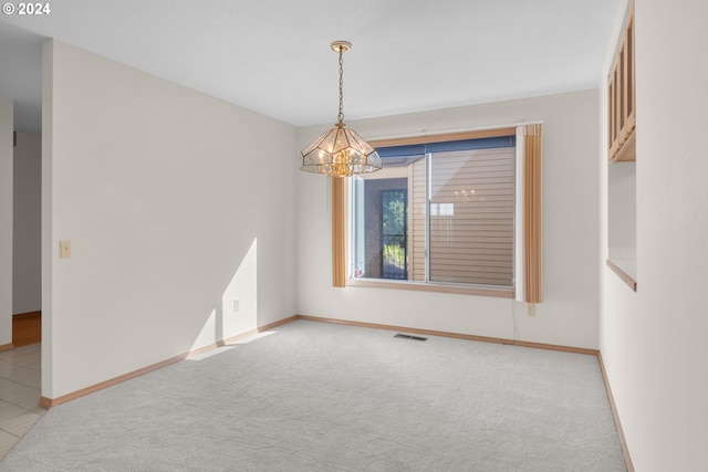 carpeted empty room featuring a notable chandelier