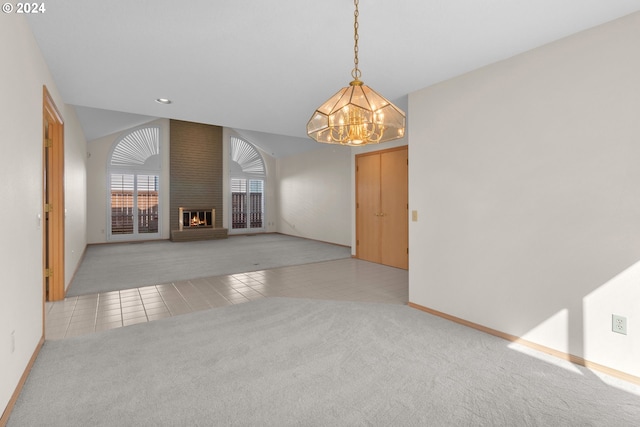 tiled empty room featuring a fireplace, lofted ceiling, and a chandelier