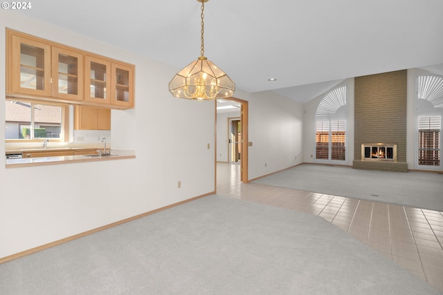 unfurnished living room with sink, vaulted ceiling, a fireplace, an inviting chandelier, and light tile patterned floors