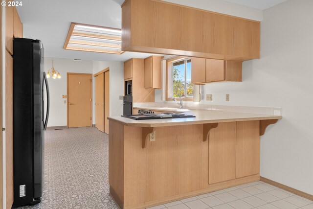 kitchen with light brown cabinetry, a kitchen bar, kitchen peninsula, and black appliances