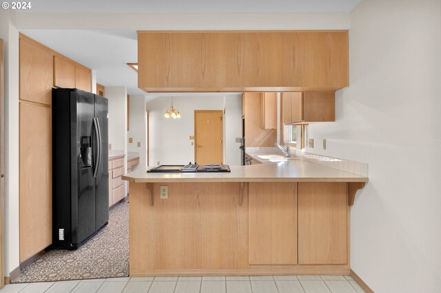 kitchen featuring pendant lighting, black fridge, sink, stainless steel gas stovetop, and kitchen peninsula