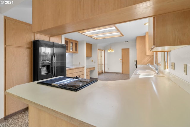 kitchen with light brown cabinets, a skylight, sink, kitchen peninsula, and black appliances