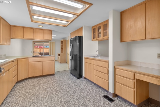 kitchen featuring built in desk, sink, kitchen peninsula, black appliances, and light brown cabinets