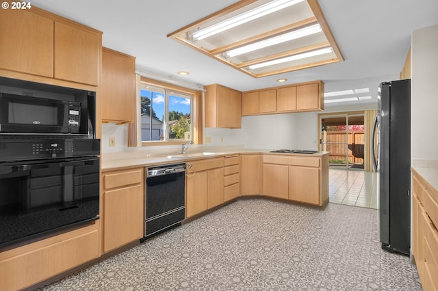 kitchen featuring kitchen peninsula, light tile patterned floors, black appliances, light brown cabinetry, and sink