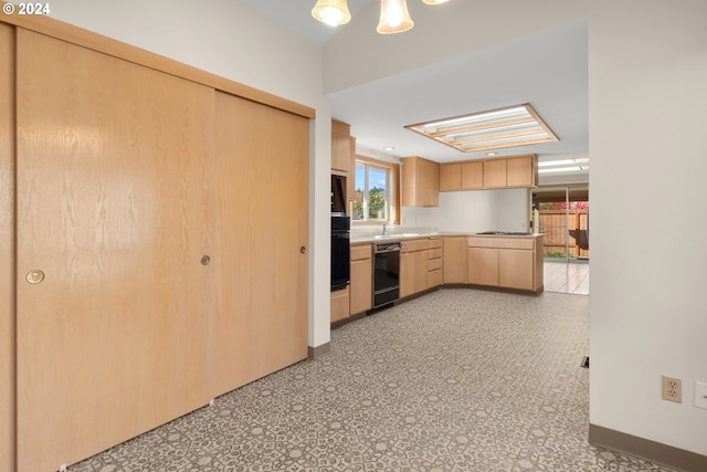 kitchen featuring light brown cabinetry, a skylight, sink, and black appliances