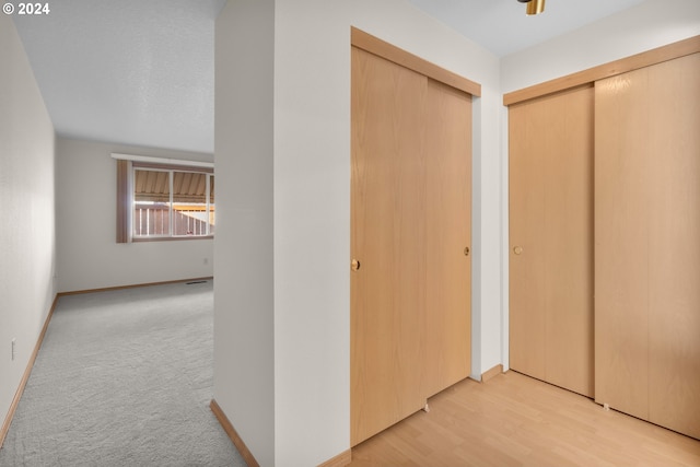 hallway featuring light hardwood / wood-style floors and a textured ceiling