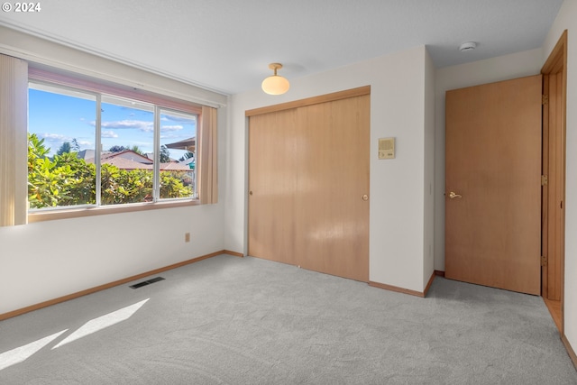 unfurnished bedroom featuring light carpet and a closet