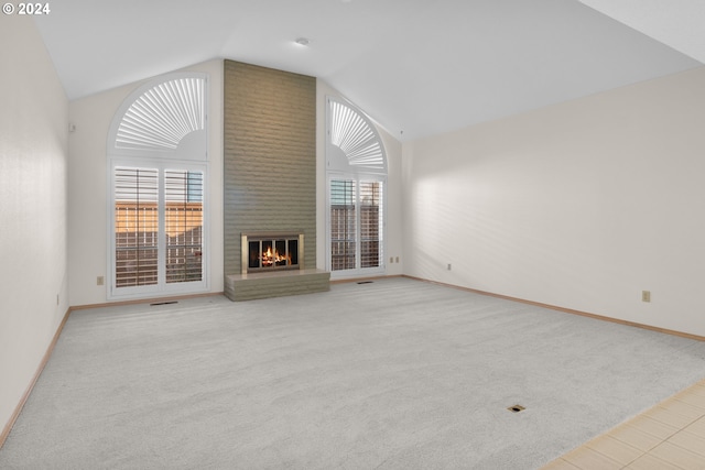 unfurnished living room featuring a brick fireplace, light colored carpet, and vaulted ceiling