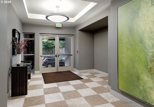 interior space with a tray ceiling and french doors