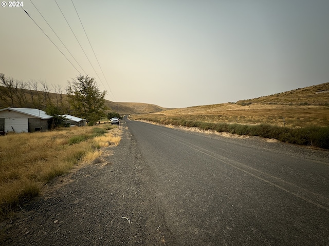 view of road with a rural view and a mountain view