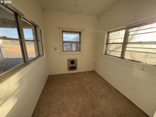 carpeted spare room with brick wall