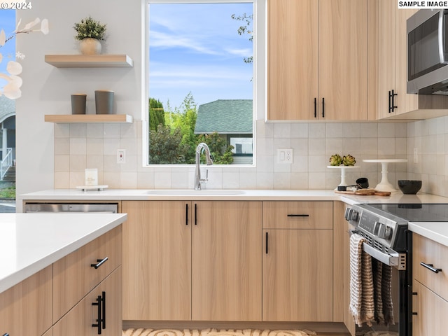 kitchen featuring decorative backsplash, light brown cabinets, sink, and range