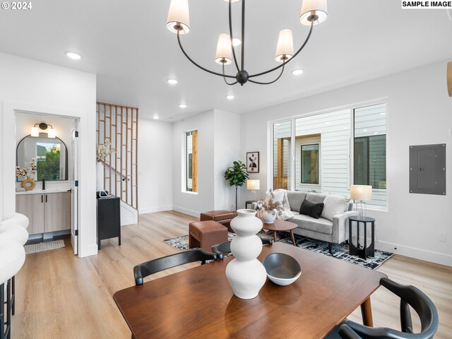 dining room featuring electric panel, light wood-type flooring, and an inviting chandelier