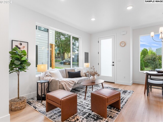 living room with hardwood / wood-style floors, plenty of natural light, and an inviting chandelier