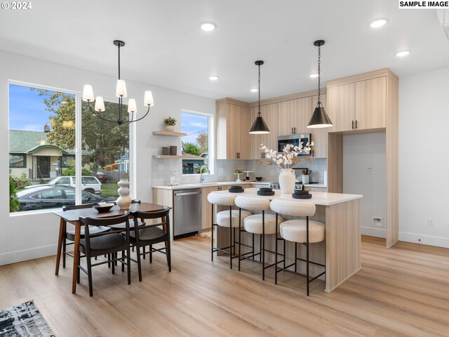 kitchen with stainless steel appliances, light hardwood / wood-style floors, a healthy amount of sunlight, and a center island