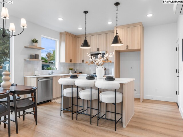 kitchen featuring stainless steel appliances, pendant lighting, light brown cabinets, and light hardwood / wood-style flooring