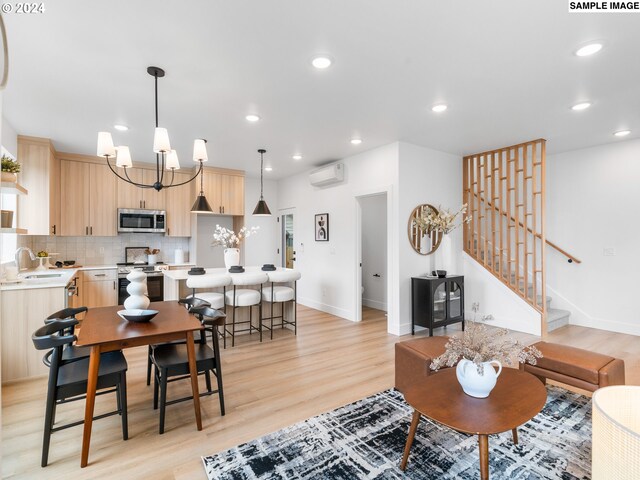 living room with light hardwood / wood-style floors, a notable chandelier, sink, and a wall mounted air conditioner