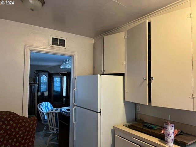 kitchen featuring white fridge and white cabinetry