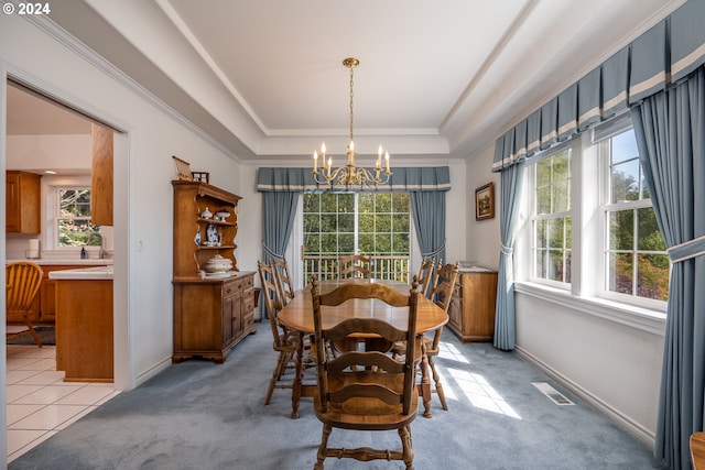 dining room featuring light carpet, visible vents, a tray ceiling, and a chandelier