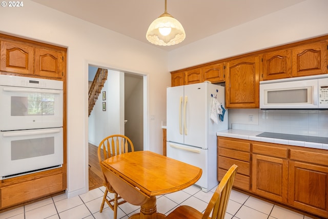 kitchen featuring white appliances, tasteful backsplash, light tile patterned floors, and brown cabinetry