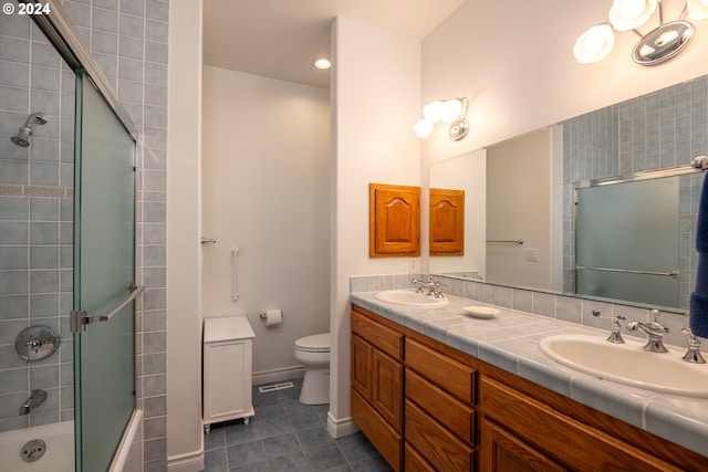 bathroom with double vanity, tile patterned flooring, a sink, and toilet