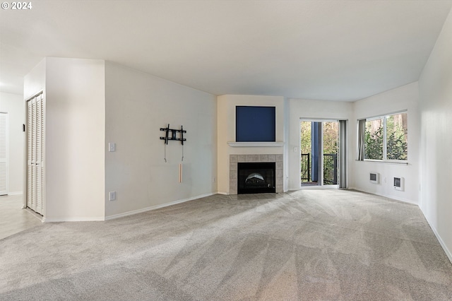 unfurnished living room with a tile fireplace and light carpet