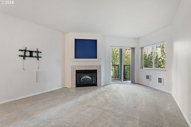 unfurnished living room featuring light colored carpet and a tile fireplace