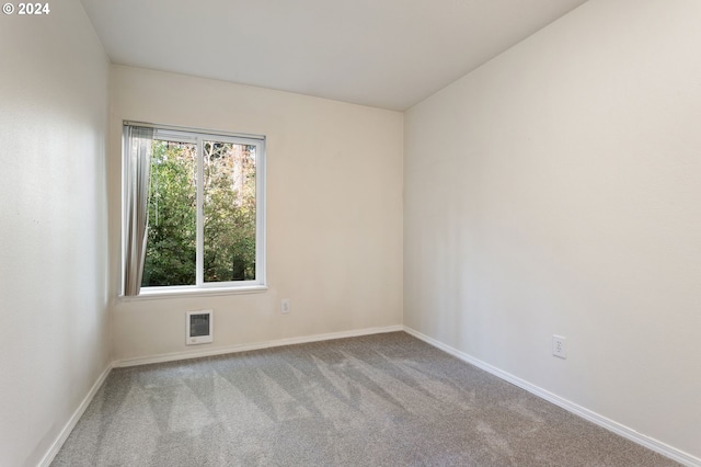 empty room featuring light carpet and heating unit